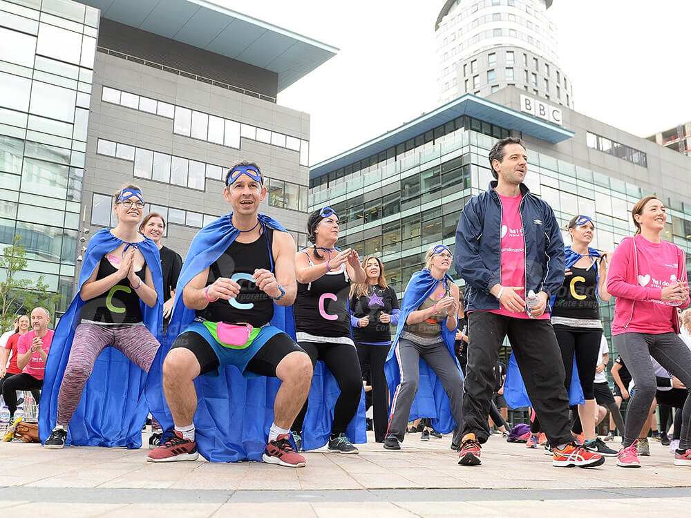 Team in capes warming up by BBC building for It's a Knockout team build