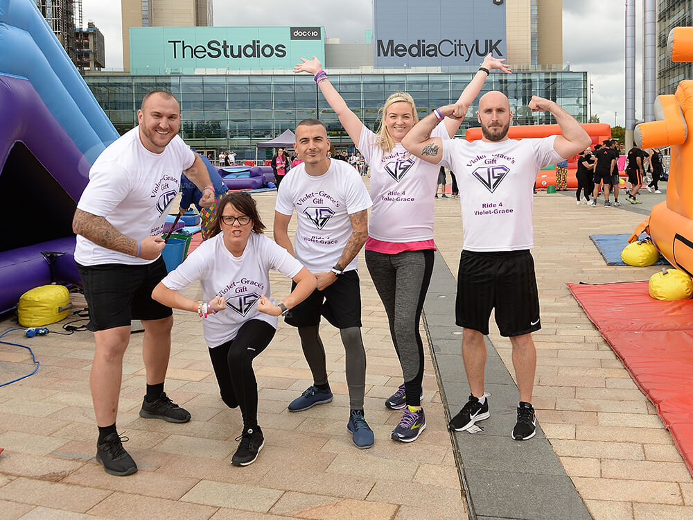 Team in white t shirts posing at Media City UK taking part in It's a Knockout team event