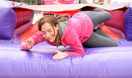 Lady laughing on inflatable for It's a Knockout team building event