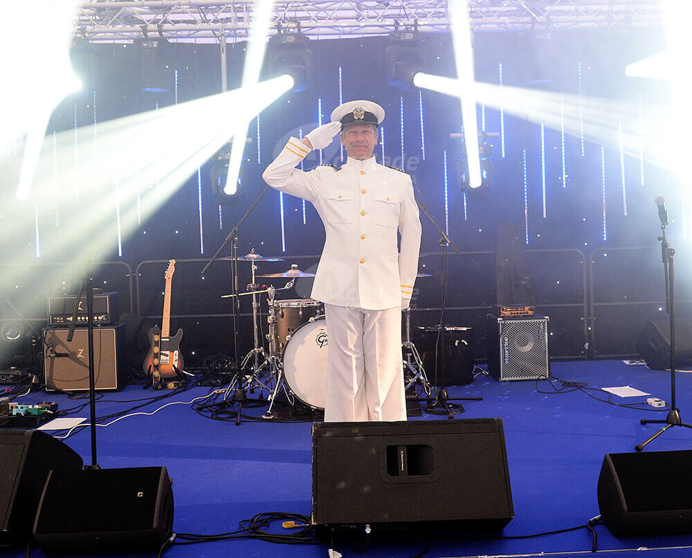 Captain on stage saluting at evening corporate event