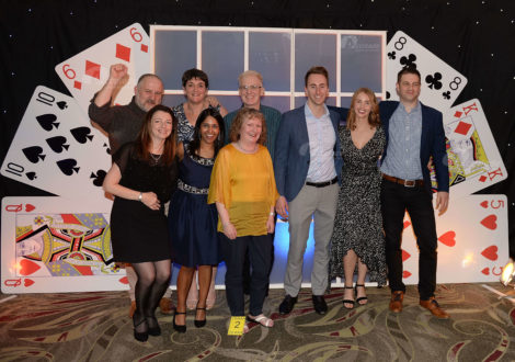 Team in front of giant card wall at Play your cards